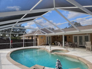 Aluminum pool screen enclosure covering a backyard swimming pool in Florida