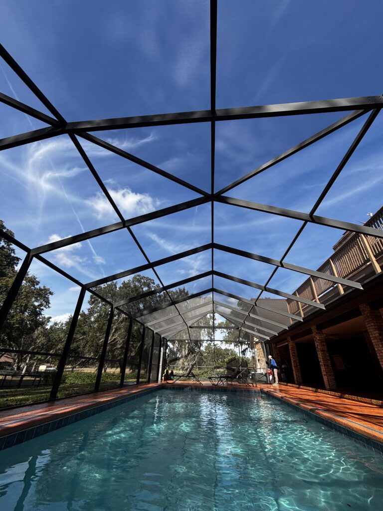 Aluminum pool screen enclosure covering a residential backyard pool in Florida