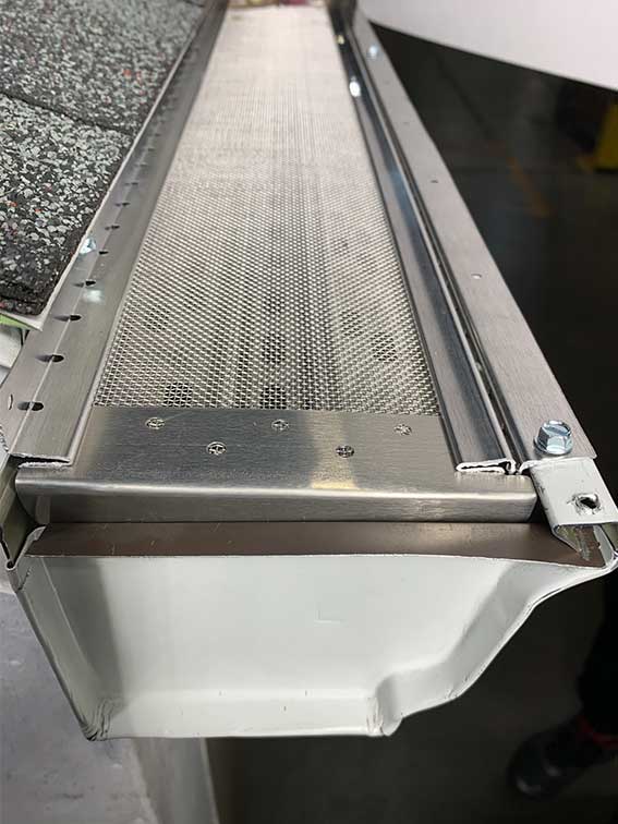 Aluminum gutter guard installed inside seamless gutter to prevent debris buildup