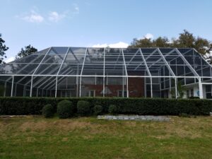 Large aluminum pool screen enclosure surrounding backyard pool