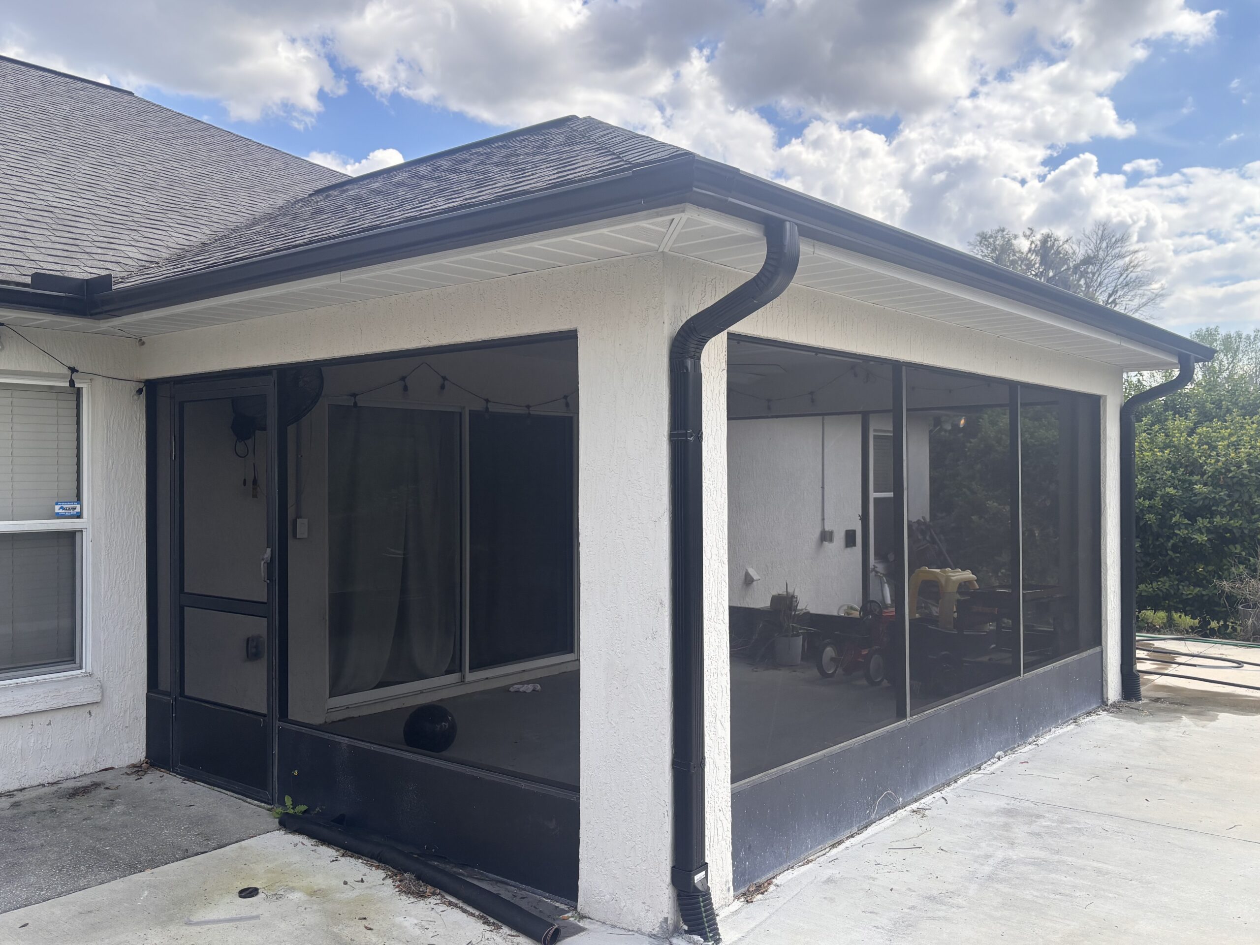 Black aluminum gutters installed along roof edge of screened patio in Florida
