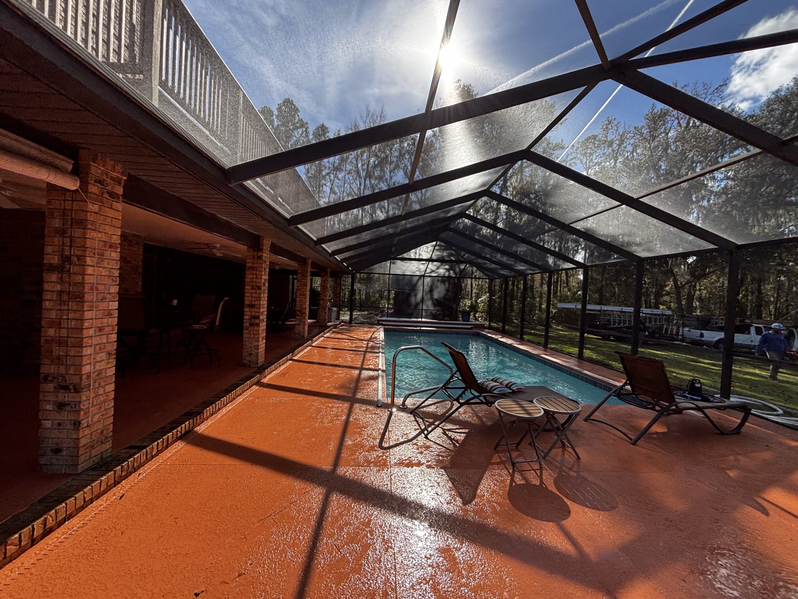 Black aluminum pool screen enclosure protecting a Florida backyard pool from bugs and debris